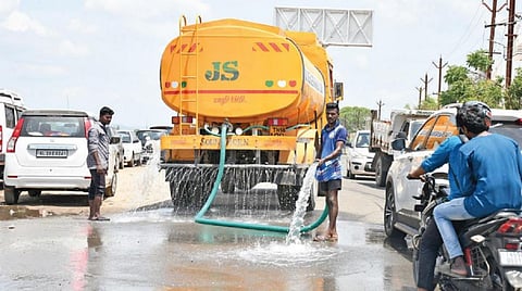 சுட்டெரிக்கும் வெயிலால், லாரி தண்ணீரை ஊற்றி நகர் சாலைகளை குளிர்விக்கின்றனர். இடம்: மதுரை வைகை வடகரை சாலை. படம்: எஸ்.கிருஷ்ணமூர்த்தி