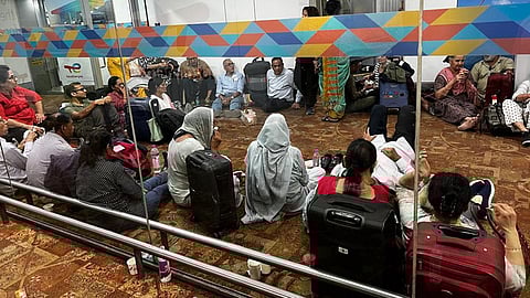 தரையில் அமர்ந்துள்ள பயணிகள்