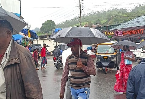 மூணாறில் பெய்து வரும் தொடர் மழையினால் அத்தியாவசியத் தேவைகளுக்காக குடைகளுடன் செல்லும் பொதுமக்கள். | இடம்:பெரியபாலம் அருகே. | படம்: என்.கணேஷ்ராஜ்.