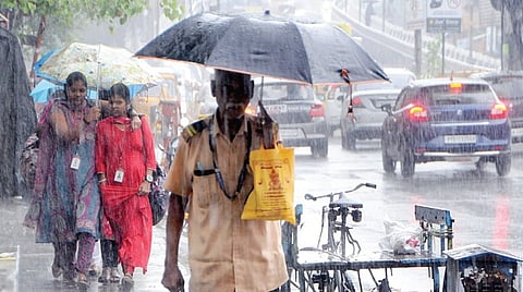 சென்னை கோடம்பாக்கத்தில் நேற்று பெய்த மழையில் குடைபிடித்தபடி செல்லும் மாணவிகள். | படம்: ம.பிரபு |