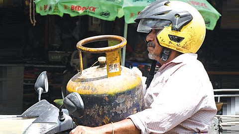 வணிக பயன்பாட்டுக்கான காஸ் சிலிண்டரை வாகனத்தில் எடுத்து செல்லும் தொழிலாளி. 