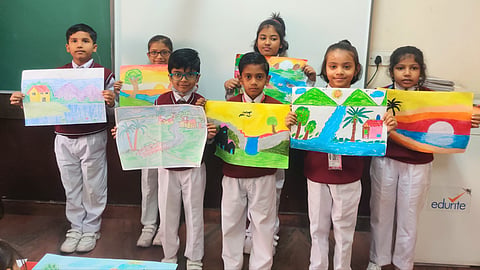 School children in India holding up their colourful artwork during an art competition.