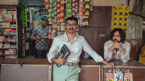 Sakre holding an sampler device alongside Galat Admi inside a neighborhood corner store.
