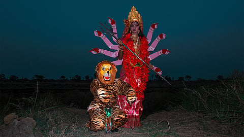 Group photograph of Munmun Bairagya and Bandana Chowdhury Byadh, dressed as the Hindu goddess Durga and Tiger, Durga’s Vahana. Near Mayurakshi River, near Khapi Maa Kali Mandir, outside Bishaypur, Birbhum, West Bengal, India