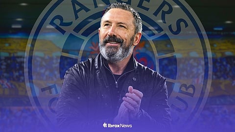 Derek McInnes applauds, with a Rangers badge behind him