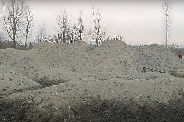 Workers have piled up sand and gravel taken from rivers in Kashmir. The large heaps show how mining is changing the land and hurting the environment. 