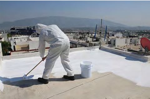  A man using white paint to convert a traditional roof into cool roof