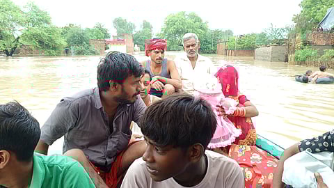 मल्लेपुर गांव के लोग बाढ़ से बचने के लिए अपने परिवार को सुरक्षित स्थान पर जाते हुए।