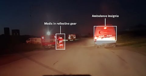 A medic in reflective gear braces near glowing ambulances, captured instants before the fatal Rafah clash on March 23, 2025.