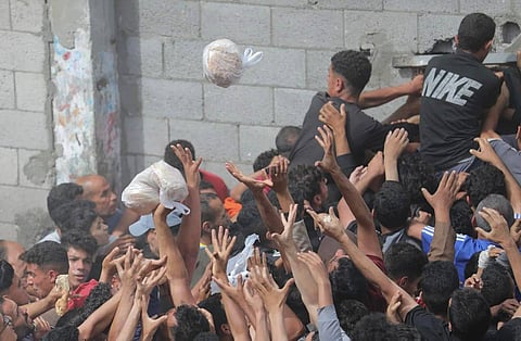 Starving Gazans reach desperately for a piece of bread.