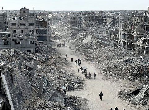 Displaced Palestinians near the rubble of buildings destroyed by Israeli bombardment.