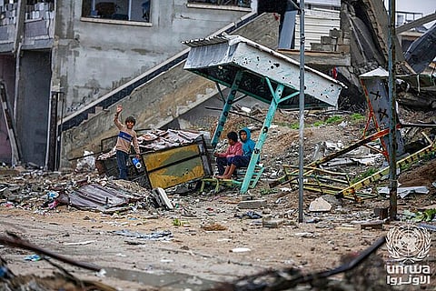Displaced children sit on the rubble of their destroyed home in Nuseirat camp, Gaza Strip.