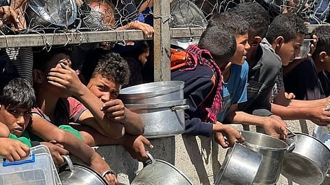 Gazans clutch utensils in desperate wait for food at aid distribution points while starving.
