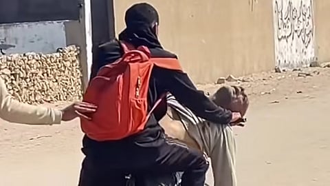 A son transporting his deceased father on a bicycle in Gaza, following the father's death near an aid distribution point, which many describe as "kill zones".