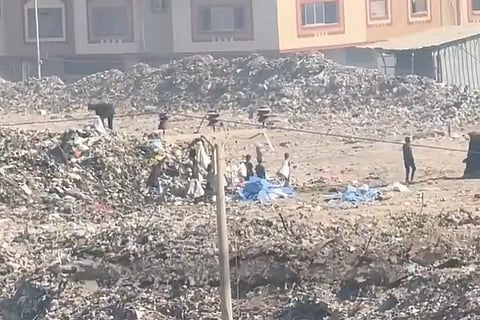 Children in Gaza gathering at overflowing garbage dump, searching for food.