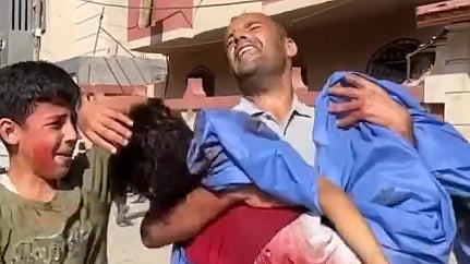  A grieving father clutches the body of his child, killed in the Israeli direct strike on a water distribution point in Al-Nuseirat camp.