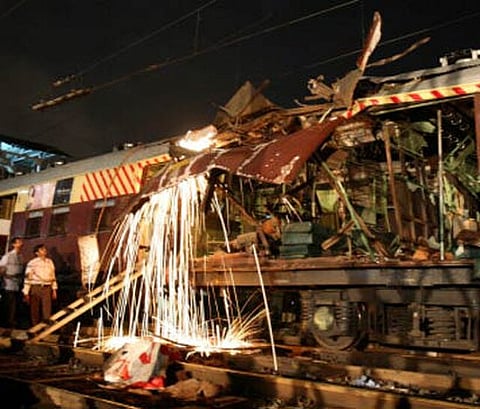 Workers cut damaged part of a local train compartment hit by bomb blast, Mumbai, 2006.