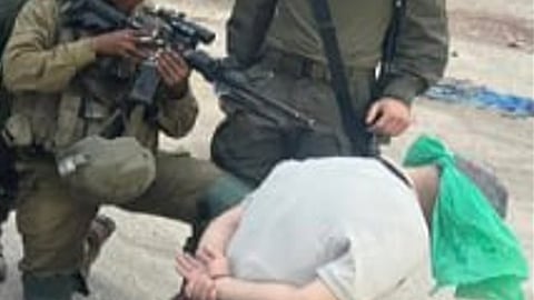 A Palestinian civilian at gunpoint, abducted during raids in the occupied West Bank.