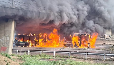 Intense flames and thick smoke engulf multiple vehicles under an overpass during the 'Block Everything' protests in France.
