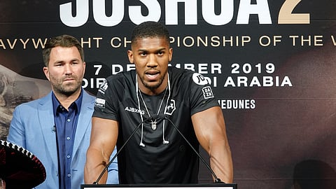 Anthony Joshua speaks at a press conference announcing his rematch with Andy Ruiz Jr. Promoter Eddie Hearn looks over Joshua's shoulder, on September 5, 2019.
