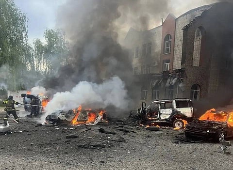A firefighter works at the scene of destroyed vehicles and a damaged building following a Ukrainian drone strike.