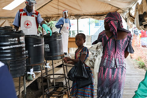 A young girl washes her hands in an Ebola prevention checkpoint supported by UK aid at a Ugandan border crossing point with the Democratic Republic of the Congo, August 2019.