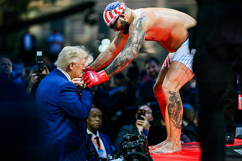 President Trump receiving and trying on a gold chain with a pendant from shirtless UFC fighter Josh Hokit, on the White House lawn.