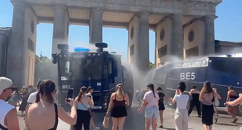 Berlin police repurposed water cannons to spray cooling mist on crowds at the Brandenburg Gate during the 40°C heatwave.