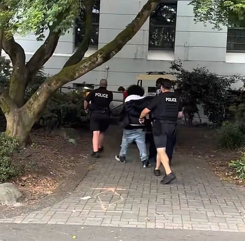 Seattle police officers escorting the handcuffed suspect.