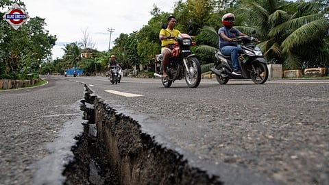 Motorists pass a crack in the road along a major highway in Tabogon town, Cebu province, central Philippines.