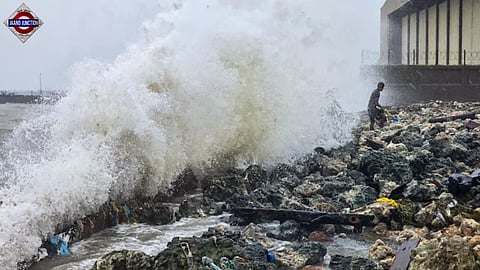 A man stands on rocks as waves crash against the seaside during rough sea conditions triggered by Cyclone Ditwah in Ramanathapuram. 