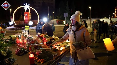 A woman leaves flowers outside the 'Le Constellation' bar, after a fire and explosion during a New Year's Eve party where several people died.