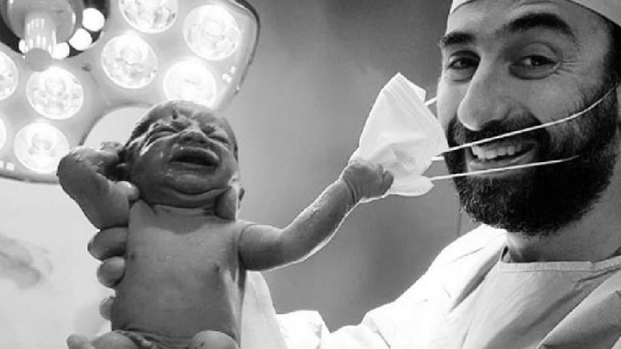 மருத்துவரின் முகக் கவசத்தை பிடுங்கும் பிறந்த குழந்தை : வைரலாகும் புகைப்படம் ! #Symbol_Of_Hope