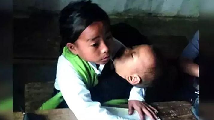 கையில் சகோதரனுடன் பள்ளியில் பாடம் கற்கும் ஒன்றாம் வகுப்பு சிறுமி.. வைரல் புகைப்படத்தின் பின்னணி !