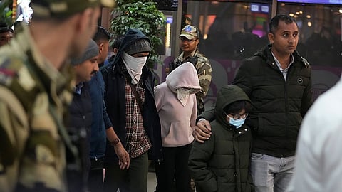 Indian police officials escort immigrants, wearing mask, deported from the United States