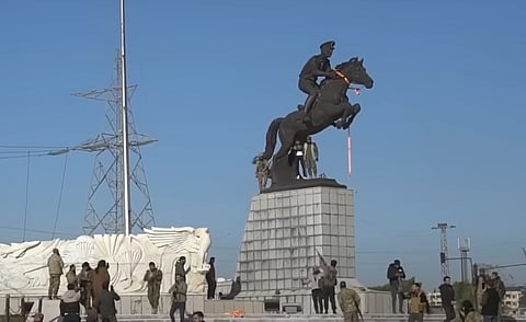 Syrian rebels gather around an equestrian statue of Bassel al-Assad at Al- Basel roundabout, western Aleppo, during the 2024 Battle of Aleppo. The statue was torn down later that day. Photo/Public Domain
