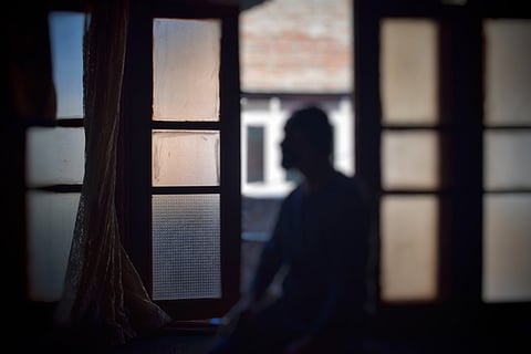 A pellet gun survivor sitting by the window in his house to hear the sounds in the street below in Srinagar, Kashmir.