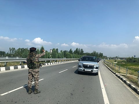 A CRPF man signals the vehicles moving towards south Kashmir along the new NH44 near Lasjan, on the outskirts of Srinagar city, to stop, as the convoy of pilgrims need to pass, on Friday July 11, 2025.