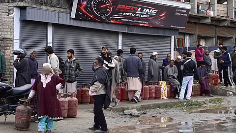 Residents queue with empty LPG cylinders outside a closed shop in Kashmir, reflecting growing anxiety over cooking gas availability as demand surges amid fears of shortage.
