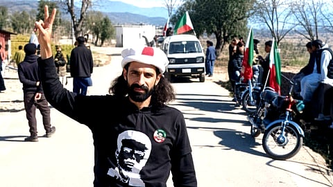 A picture of Faizan Sagheer, Jammu Kashmir Liberation Front activist, who was one of the four youth killed in an explosion on Monday, October 12, 2026, near the Line of Control in Pakistan administered Jammu and Kashmir with its flags and a vehicle in the background.