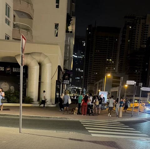 ينتظر السكان الذين تم إجلاؤهم خارج المبنى بينما تستجيب خدمات الطوارئ للحريق