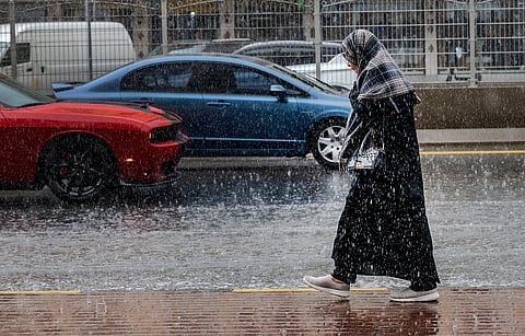 أحد المشاة يسير تحت المطر الغزير في الشارقة