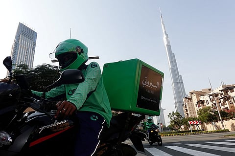 عامل توصيل يقود دراجة نارية مع برج خليفة في الخلفية، بعد هجوم إيراني، عقب ضربات الولايات المتحدة وإسرائيل على إيران