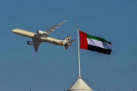 طائرة تابعة للاتحاد للطيران تحلق بجانب علم دولة الإمارات العربية المتحدة