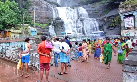 குற்றாலம் மெயினருவியில் வெள்ளம் ஆர்ப்பரித்து கொட்டுவதால் குளிக்க வந்த சுற்றுலா பயணிகள் ஏமாற்றத்துடன் நிற்கும் காட்சி.
