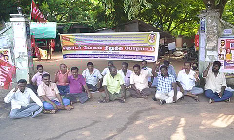 லாஸ்பேட்டை உழவர் சந்தை முன்பு ஊழியர்கள் தர்ணா போராட்டத்தில் ஈடுப்பட்ட காட்சி.&nbsp;