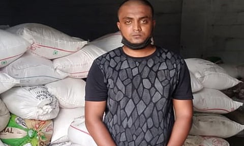 பறிமுதல் செய்யப்பட்ட ரேஷன் அரிசி மூட்டைகளுடன் கைதான கார்த்திக்கேயன்.