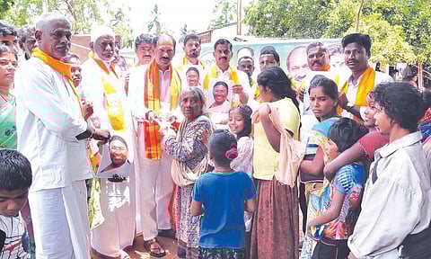 பா.ஜனதா தலைவர் சாமிநாதன் பழங்குடியினர் மக்களுக்கு சர்க்கரை வழங்கும் காட்சி.