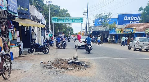 ரோட்டின் நடுவே அபாயகரமான மணல் குவியலில் கொடி நடப்பட்டிருக்கும் காட்சி