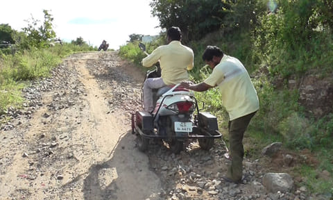 குண்டும் குழியுமாக உள்ள சாலையில் செல்ல சிரமப்படும் மாற்று திறனாளி.